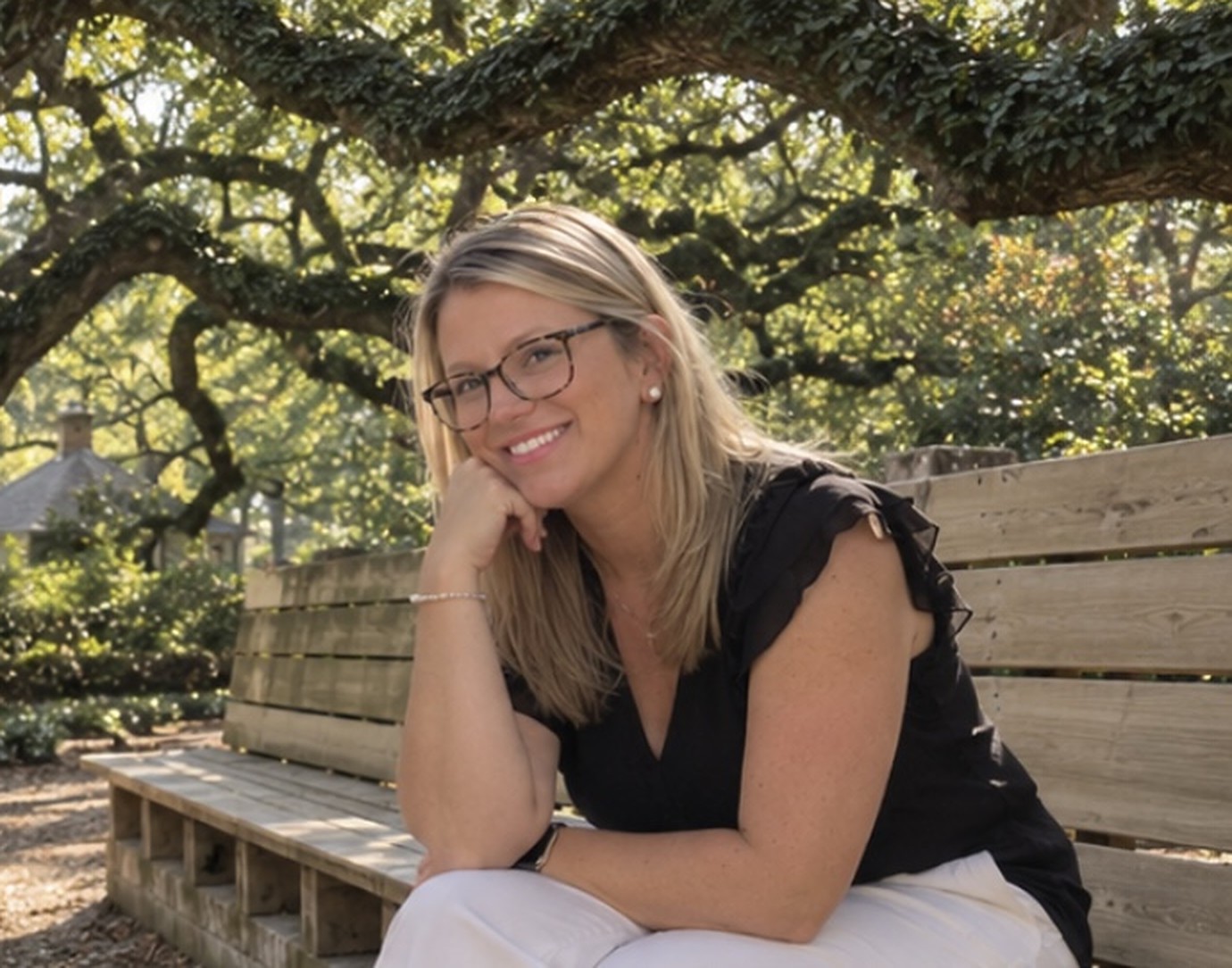 Ashley Smith Lucas, founder and owner of Magnolia Grace & Co., LLC, seated on a garden bench beneath the live oaks of Aiken, South Carolina
