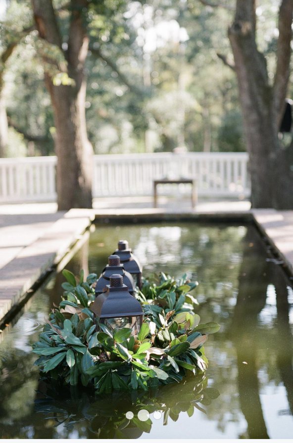 A lantern wreathed in greenery floating in a still garden pool